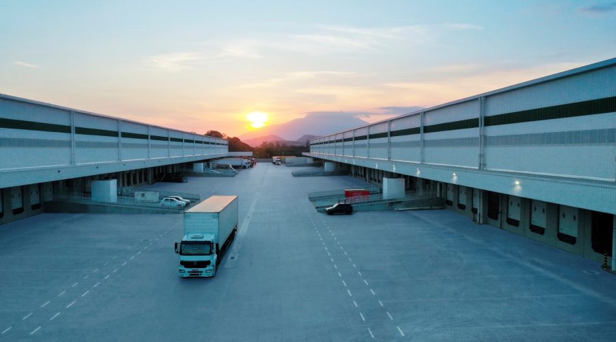 Imagem da área de docas de um galpão da GLP Brasil com carros e caminhões estacionados