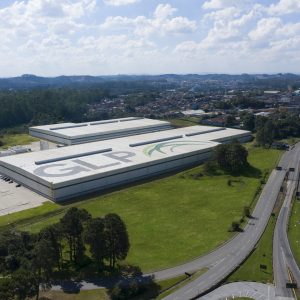 Imagem aérea de um galpão com o logo da GLP Brasil no teto e rodovias ao redor