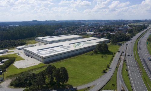 Imagem aérea de um galpão com o logo da GLP Brasil no teto e rodovias ao redor