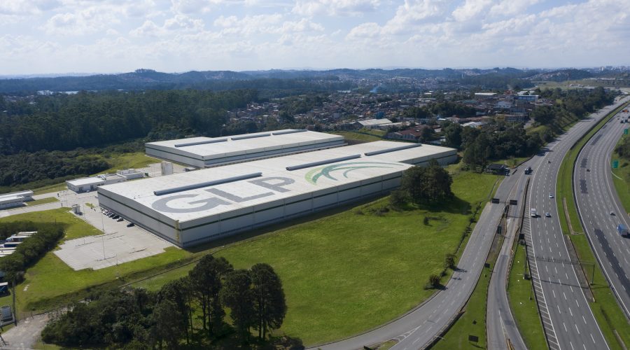 Imagem aérea de um galpão com o logo da GLP Brasil no teto e rodovias ao redor